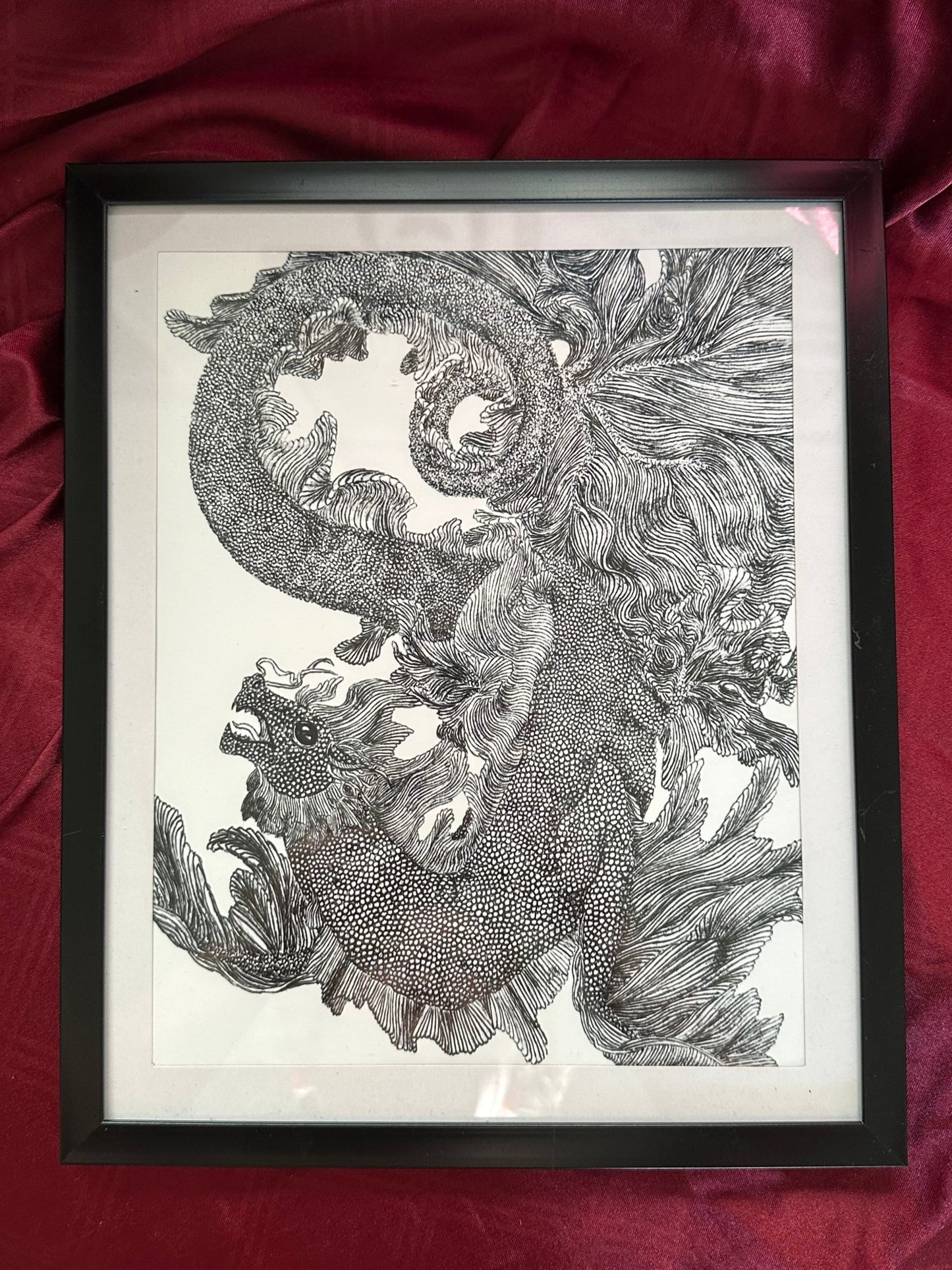 Framed detailed ink illustration featuring a black and white sea dragon twisting around itself.